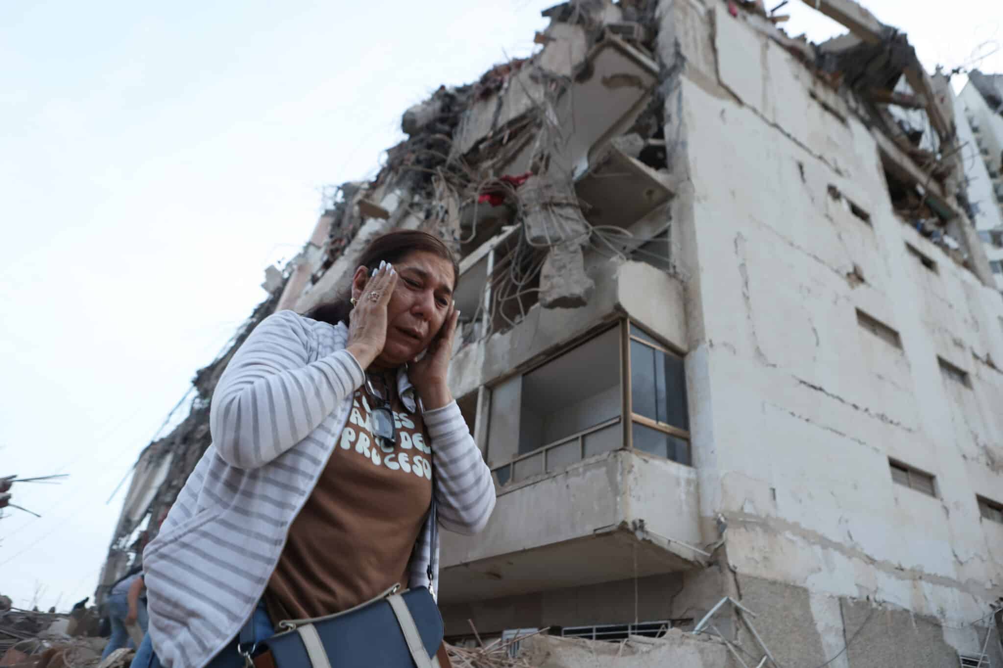 A woman walks past a building damaged during an earthquake in La Guaira, Venezuela, Thursday, June 25, 2026. (AP Photo/Pedro Mattey)